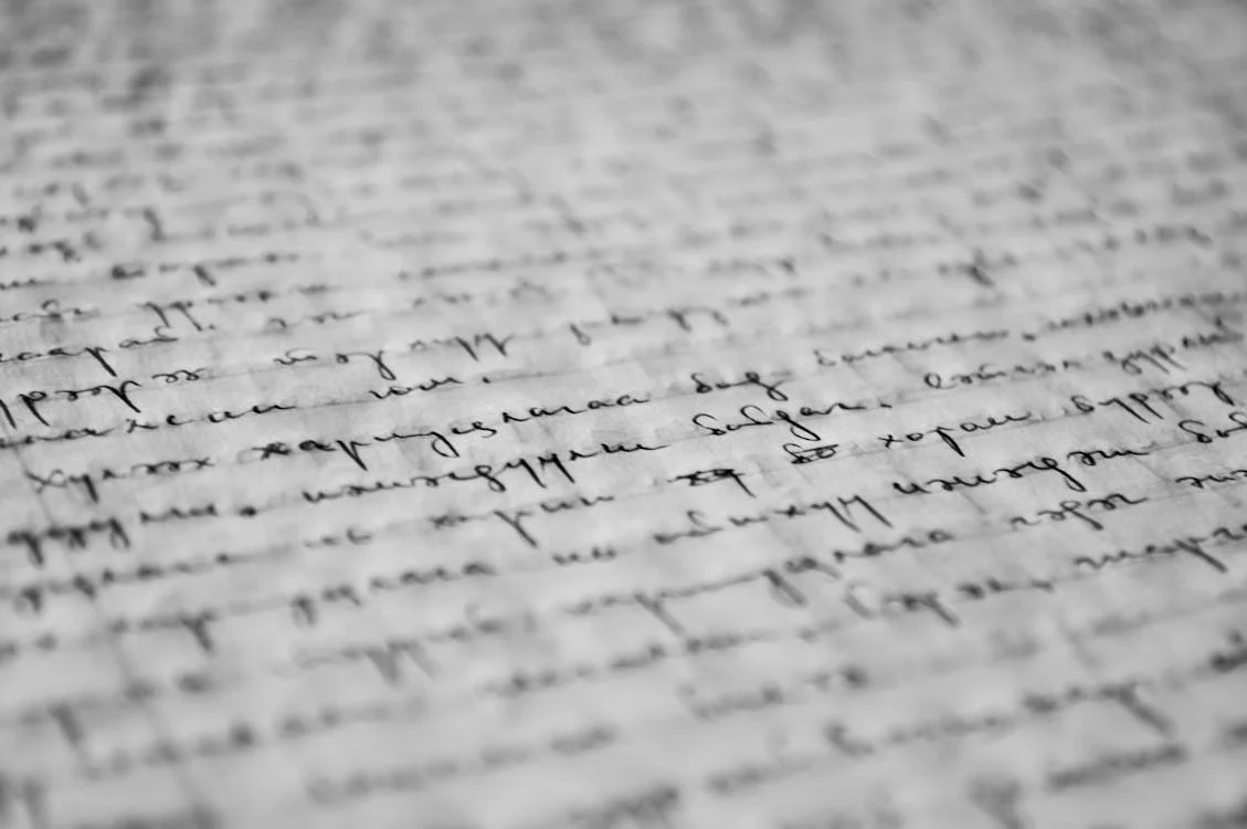 Close-up of handwritten text on paper, showing cursive writing in black ink.
